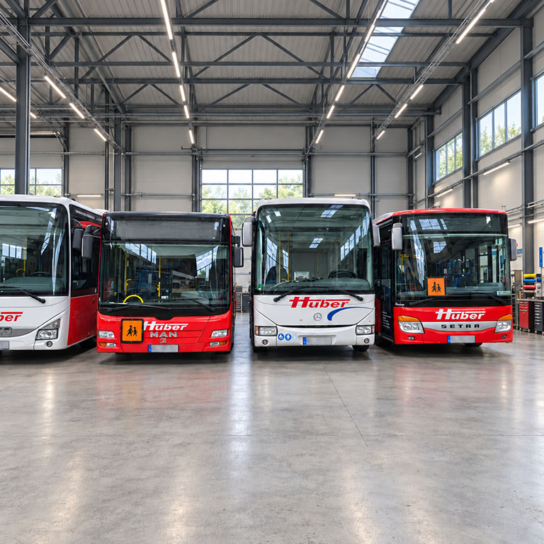 Huber-Busse mit einheitlicher Beschriftung in einer Produktionshalle